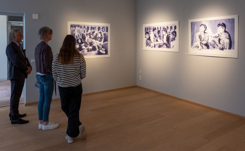 Besucher in einer Galerie betrachten kunstvolle, monochrome Gemälde von Taha Bader, die unterschiedliche Emotionen und alltägliche Momente darstellen.